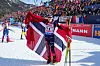 Skiskyttar Maren Hjelmeset Kirkeeide med det norske flagget rundt seg på skiskyttarstadion.